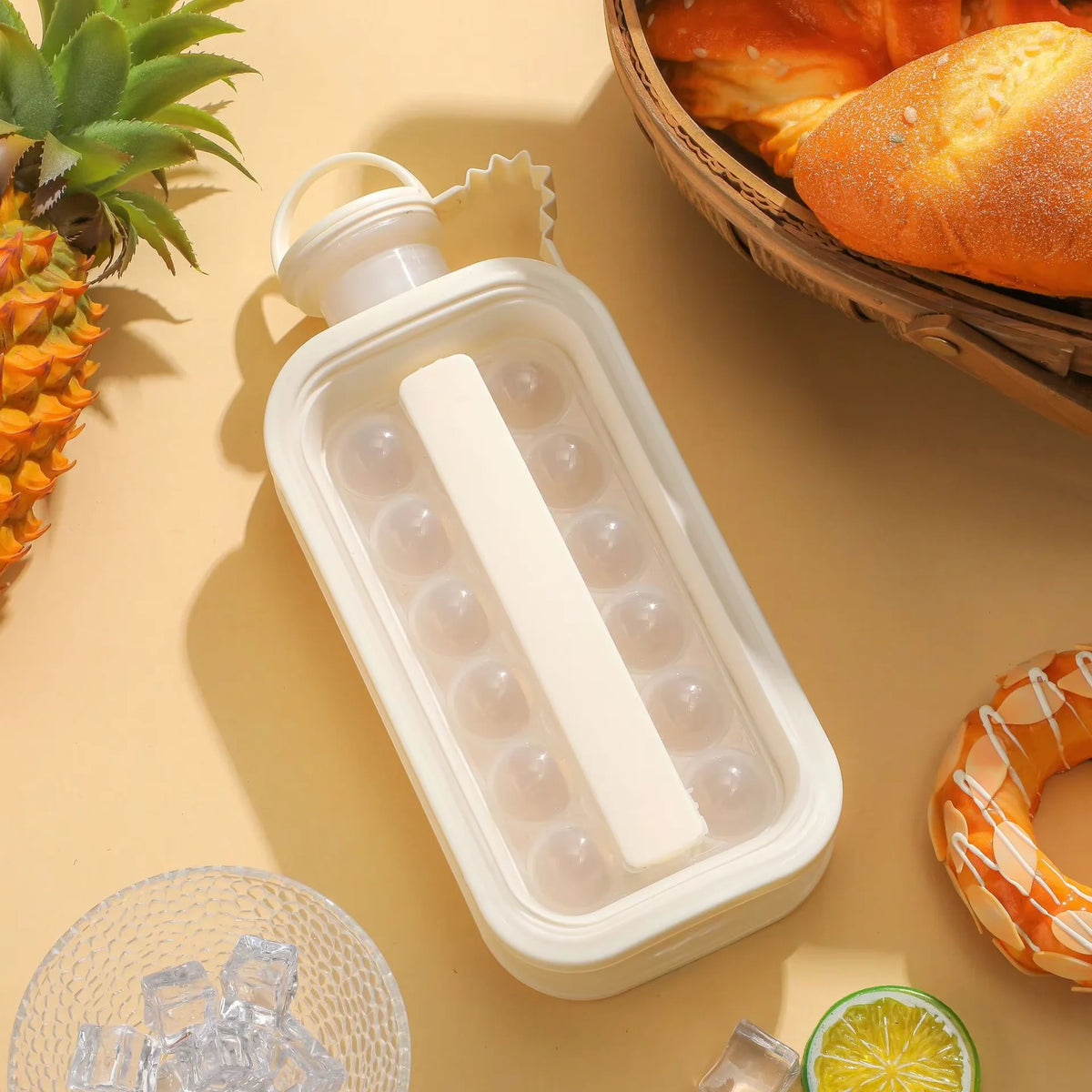 A white portable ice cube maker in a bottle design with a white ice cube, next to a pineapple and a loaf of bread.
