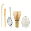 A set of natural bamboo tea tools including a scoop, a strainer, and a ceramic teapot.