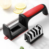 A black and red handheld knife sharpener with a silver blade is shown on a white surface.
