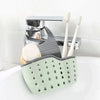 A silver adjustable sink drain hanging sponge rack with white toothbrushes and a light green sponge holder.