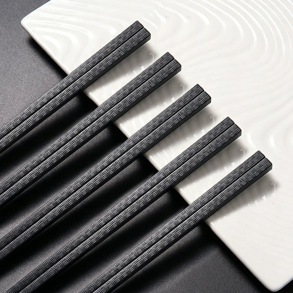 Ein Set wiederverwendbare schwarze, rutschfeste Plastik-Stäbchen auf einem weißen Teller.
