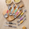 A set of nine stainless steel measuring spoons with magnetic suction cups arranged on a wooden board.