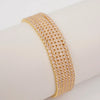 A stack of gold-toned acrylic elastic bracelets worn on a wrist.