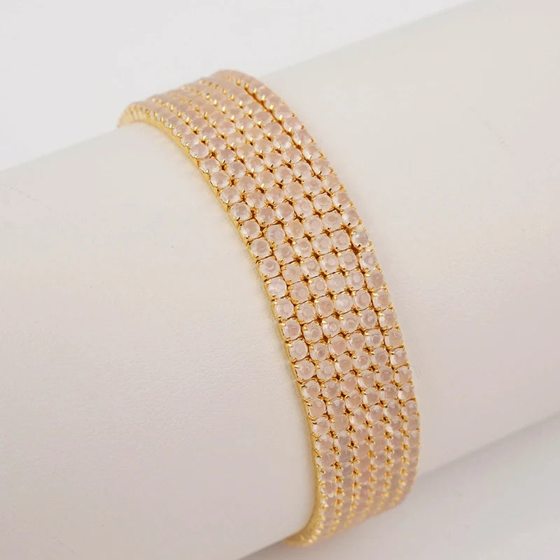 A stack of gold-toned acrylic elastic bracelets worn on a wrist.