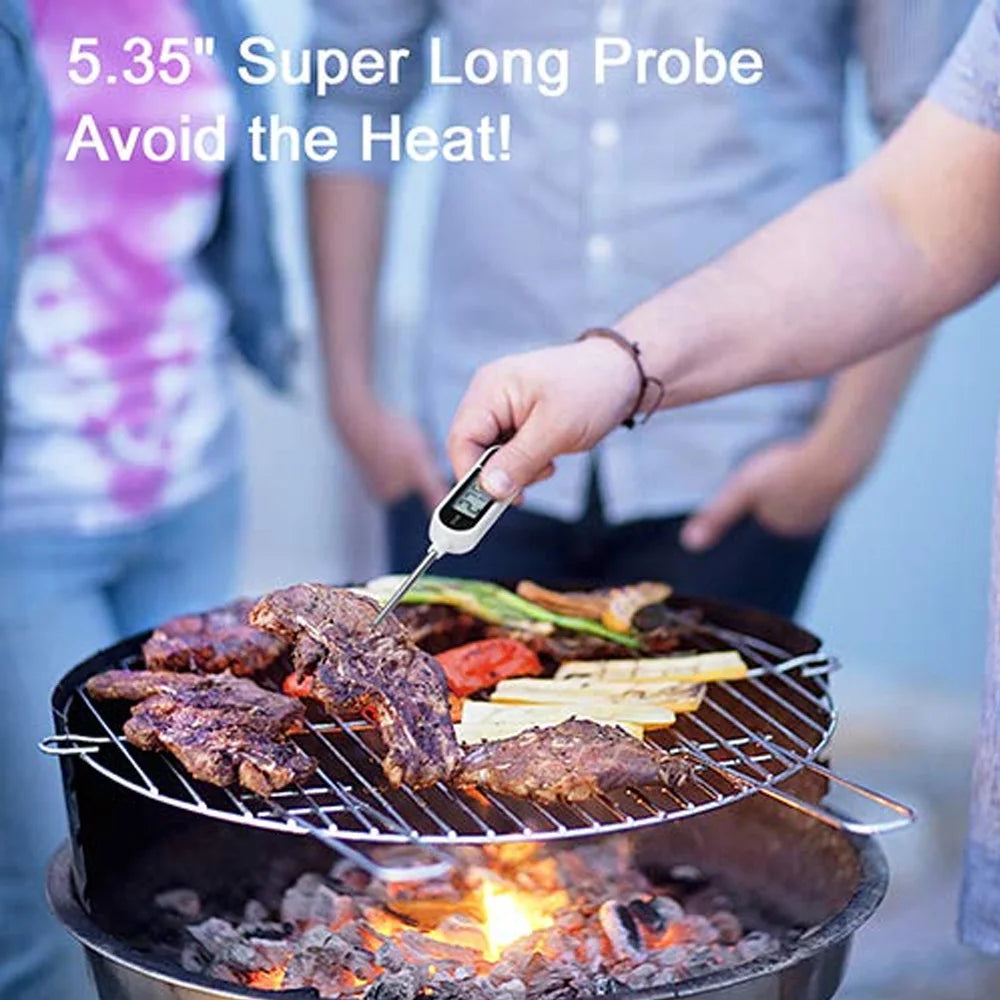 A hand holds a digital meat thermometer with a long probe over grilled meat on a barbecue grill.