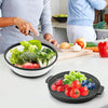 A person is cutting vegetables on a white countertop, with silicone splatter guards and fresh produce visible.