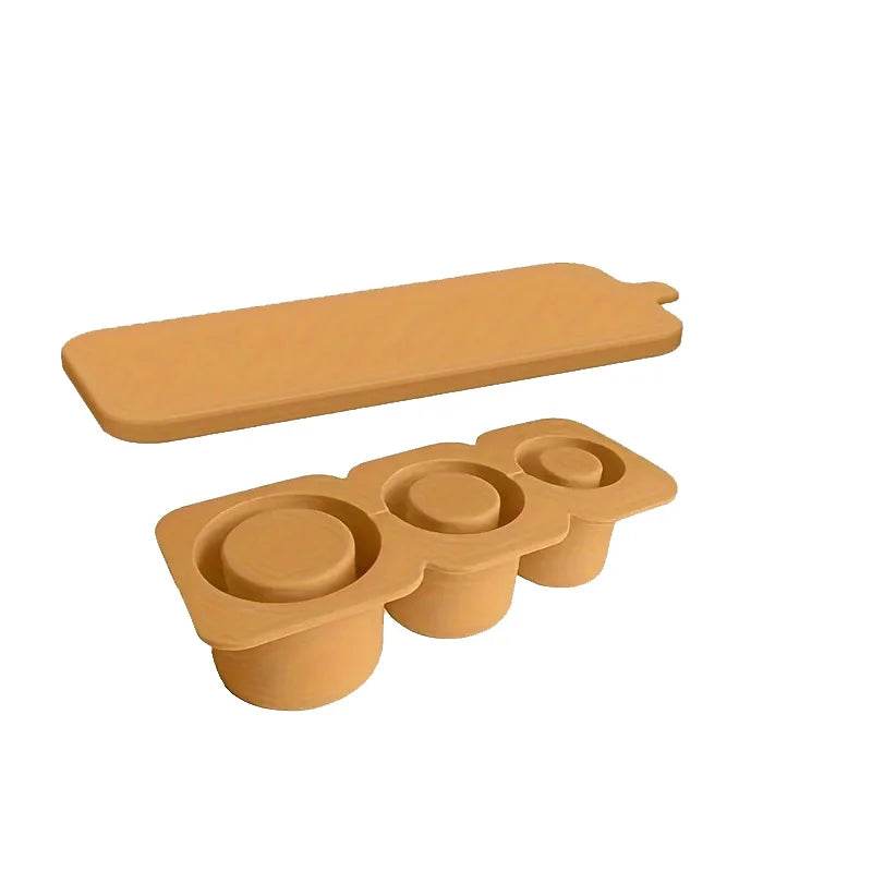 A silicone ice cube tray with three circular molds for tumblers, in a tan or beige color.