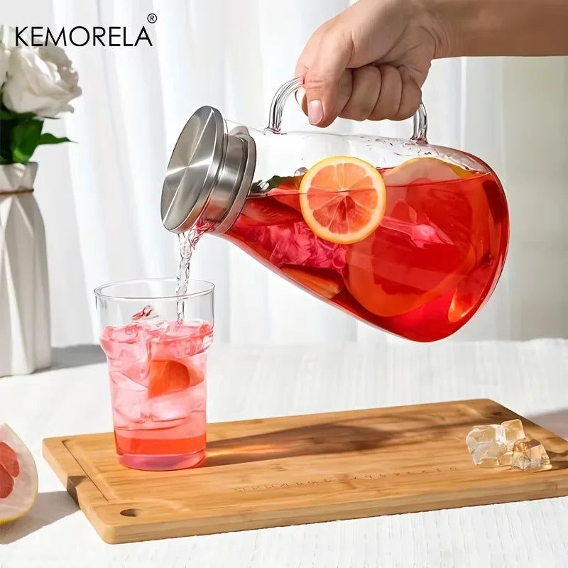 A hand pours a bright red beverage from a glass pitcher into a glass, resting on a wooden board.
