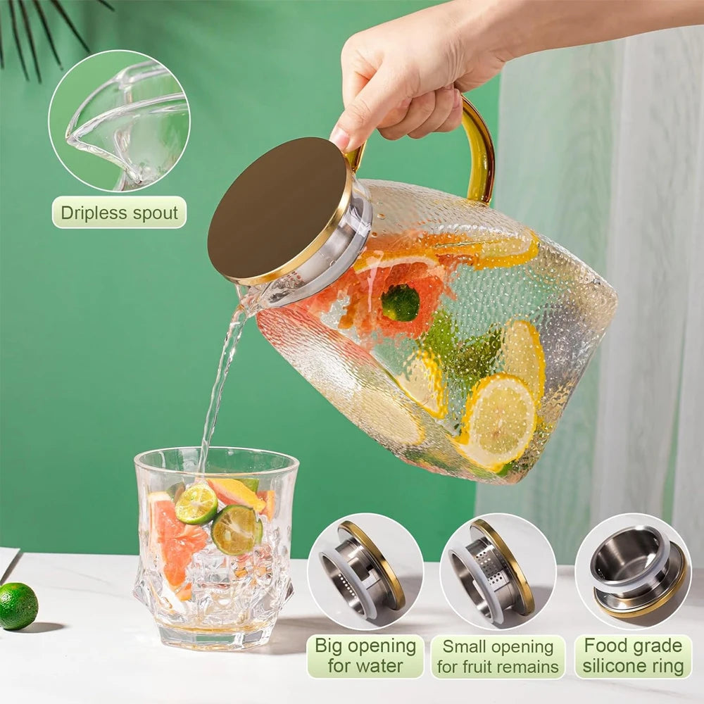 A hand pours water from a large glass jug with a lid into a glass, demonstrating a dripless spout feature.