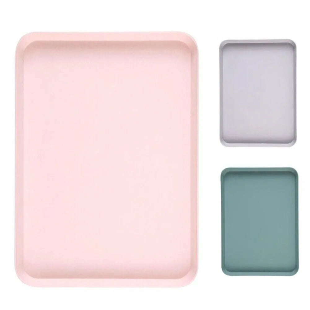 A set of three rectangular serving trays in pink, light gray, and sage green.