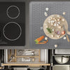 A silicone stove and cooktop protector mat is shown with various cooking utensils and ingredients on a gray surface.