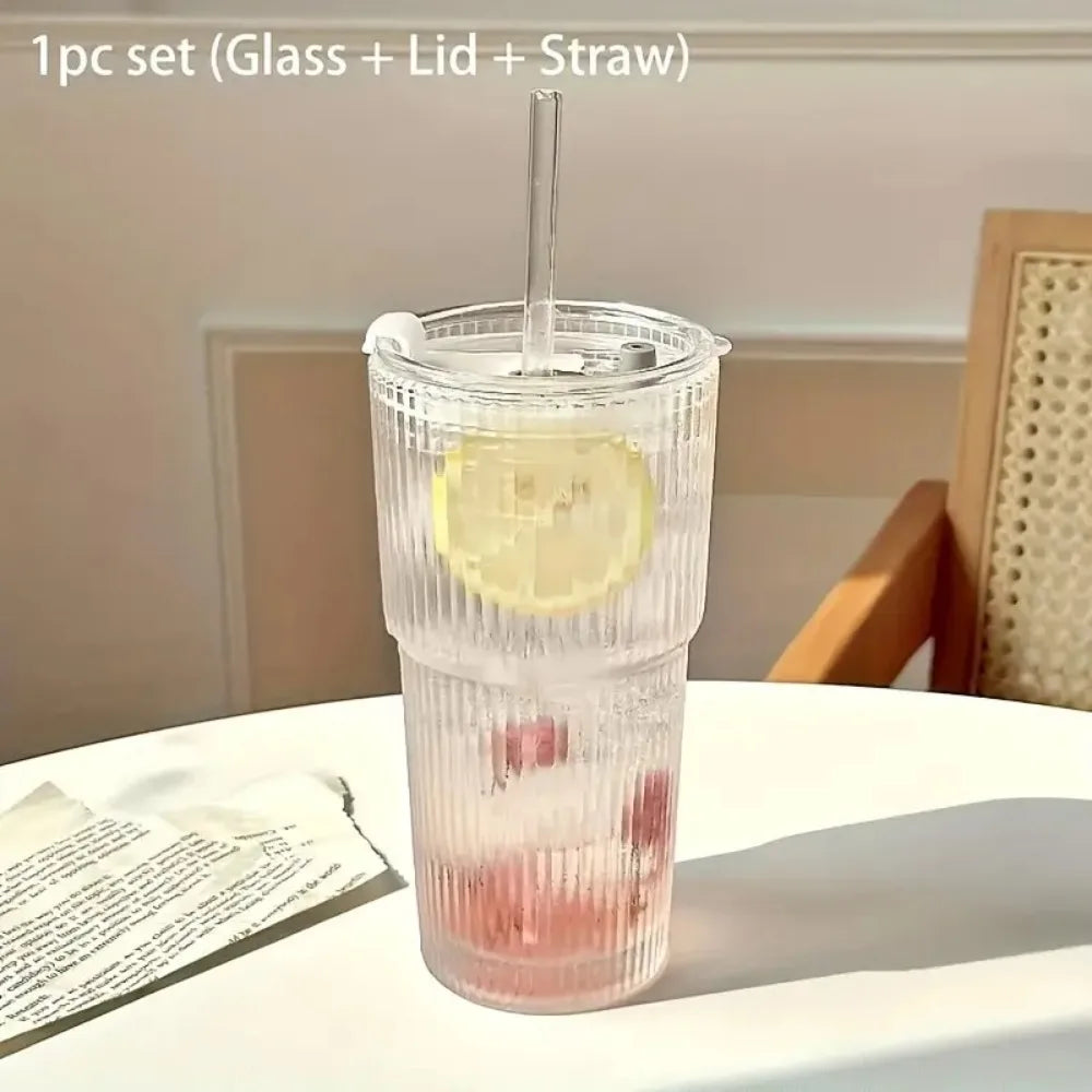 A clear glass drinking cup filled with pink liquid, featuring a lid and a straw.