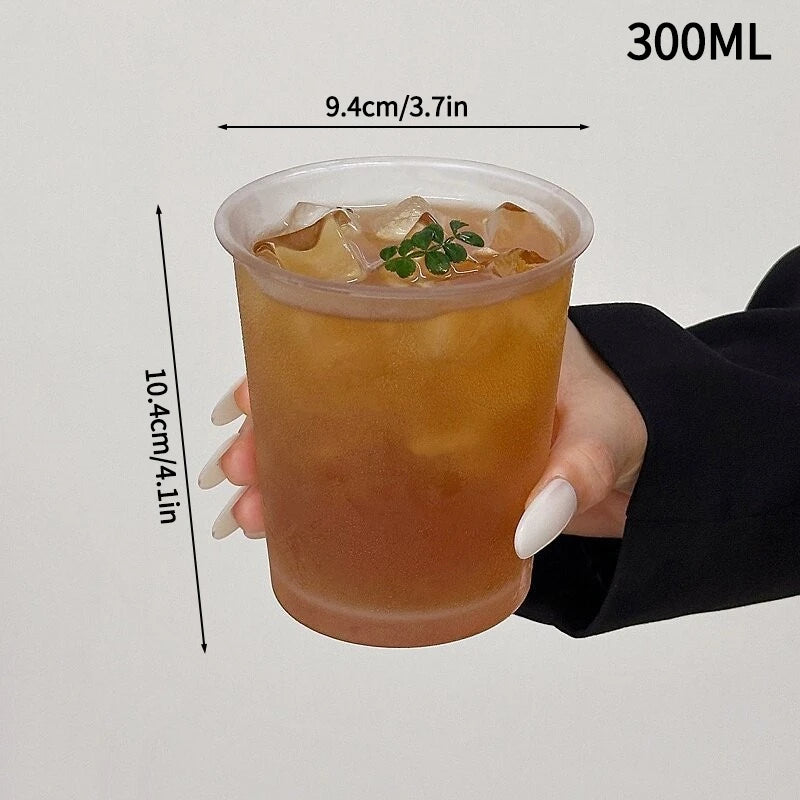 A hand holds a 300ml glass tumbler filled with iced tea or juice, showing its dimensions.