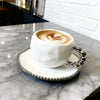 Service de tasse et soucoupe en céramique blanche avec latte art sur une table en marbre.