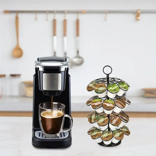 Eine schwarze Kaffeemaschine neben einem rotierenden Aufbewahrungsregal für Kapseln mit verschiedenen Kaffeekapseln.