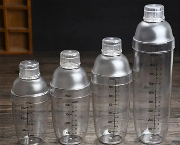 Ein Set klarer Plastik-Cocktail-Shaker in verschiedenen Größen und mit Deckeln, auf einer Holzoberfläche