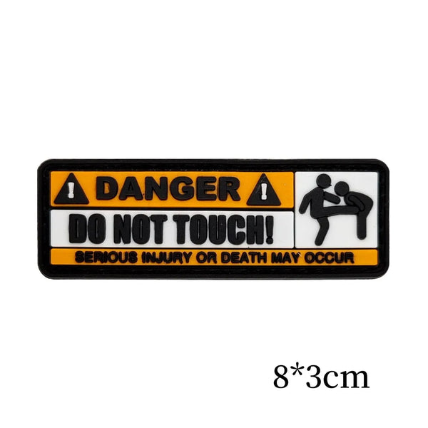 Black warning patch with yellow text and symbols indicating danger and a warning not to touch.