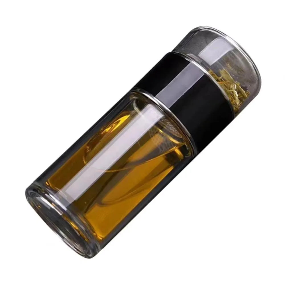 A glass tea infuser bottle filled with amber-colored tea, featuring a black cap and cork stopper.