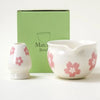 A white ceramic bowl and matching pitcher with pink floral designs displayed next to its green packaging box.