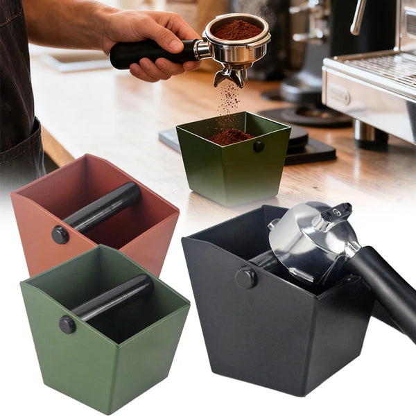 Eine Hand gießt Kaffeepulver in eine dunkelgrüne Espresso-Knockbox, mit anderen farbigen Boxen sichtbar.