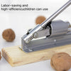 Stainless steel manual nut cracker being used to crack a nut on a wooden board.