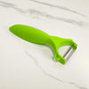 A bright lime green multi-purpose vegetable peeler knife resting on a white marble surface.