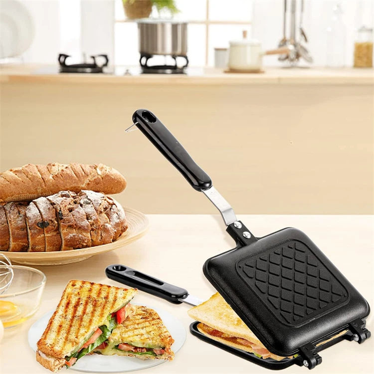 A black non-stick sandwich and grill pan is shown with grilled sandwiches and bread on a wooden surface.