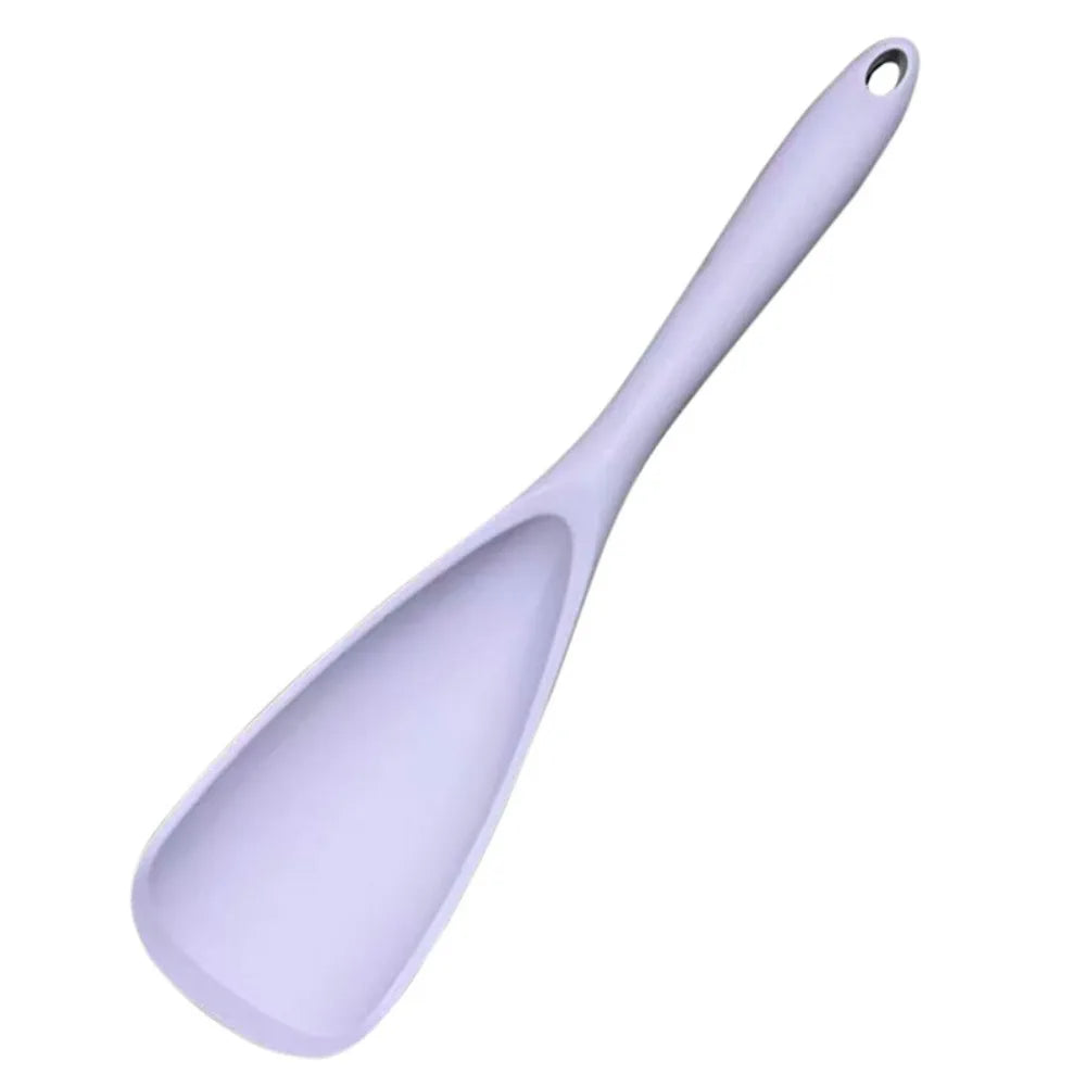 A white heat resistant silicone stirring spoon with a handle.