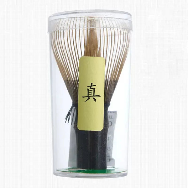 Klares Glasgefäß mit Bambus-Matcha-Kistchen mit japanischen Schriftzeichen auf gelbem Etikett.