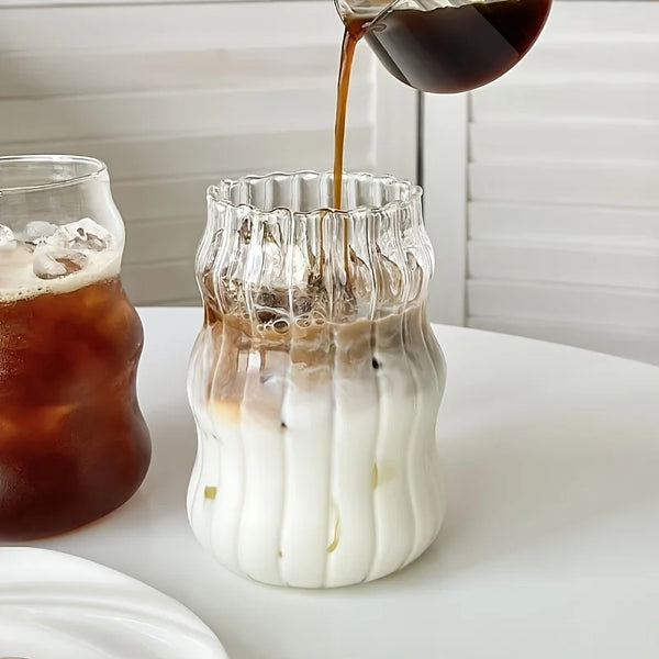 Eiskalter Kaffee wird in ein vertikales Glas mit Milch und Eis gegossen.