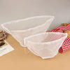 White reusable kitchen food filter bags displayed on a wooden surface next to a red and white checkered cloth.