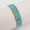 A stack of blue and gold acrylic elastic bracelets worn on a white wrist.