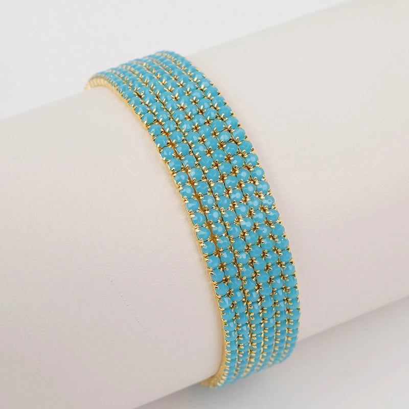 A stack of blue and gold acrylic elastic bracelets worn on a white wrist.