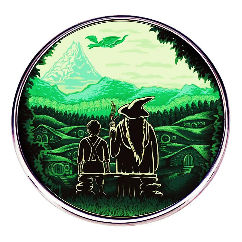 A green enamel pin featuring a wizard figure, a flying creature, and lush green landscape.