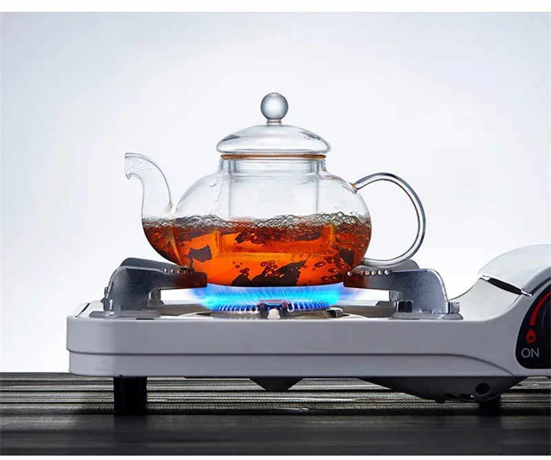 A clear glass tea pot is heating on a white electric burner, ready for brewing.