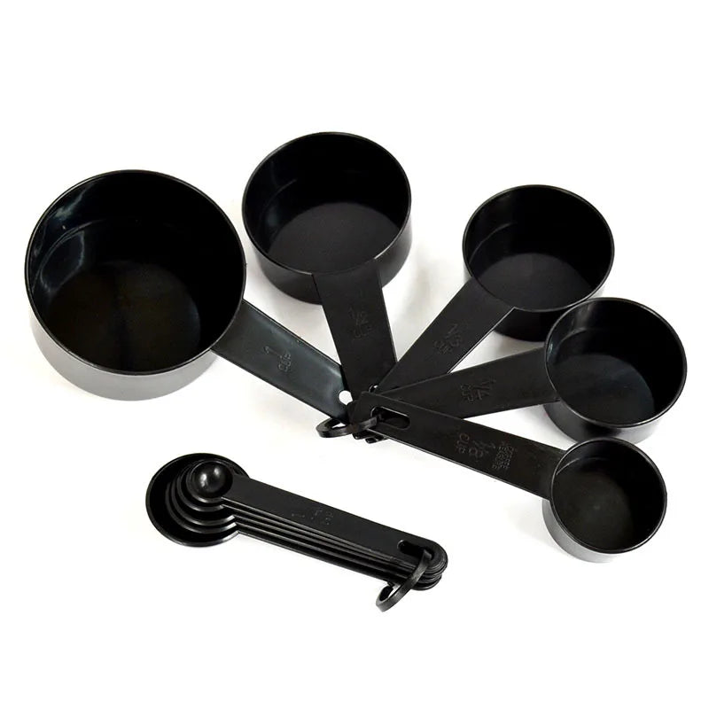 A set of black precision kitchen measuring tools including several spoons and scoops.