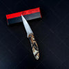 A folding utility knife with a silver blade and a wooden handle rests on a black surface next to a red and black box.