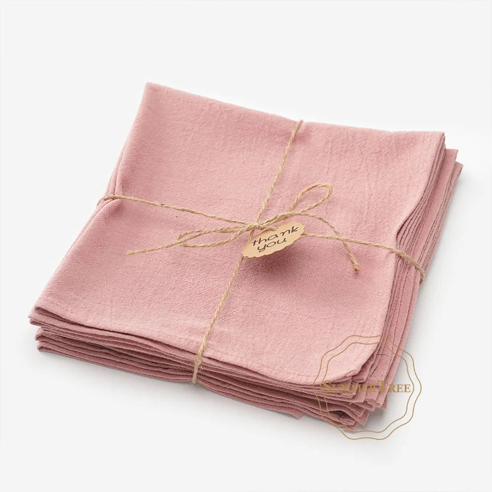 A stack of ten pink cotton table napkins tied with twine and a thank you tag.