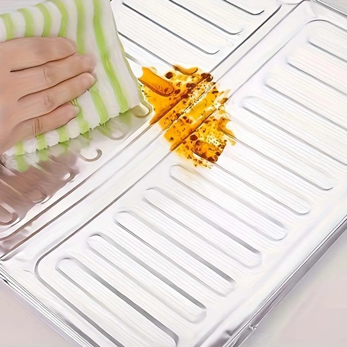 A hand is pouring yellow stir-fry oil onto a shiny metal cooktop surface.