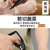 A close-up of a professional titanium kitchen shear being used to cut meat, showing the blade and the raw poultry.