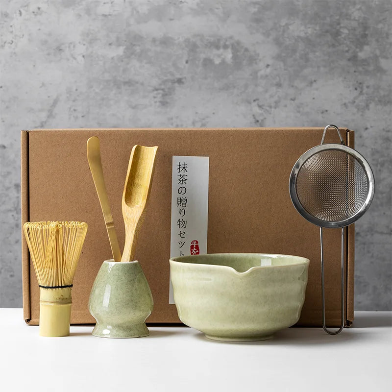 Un juego de herramientas para té matcha, incluyendo cucharas de bambú y un cuenco de cerámica, exhibido en una caja de cartón