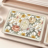 A rectangular silicone dish drying mat with a floral pattern rests in a light wooden tray.