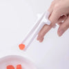 A hand holds a white precision finger chopstick with an orange tip above a pink bowl.
