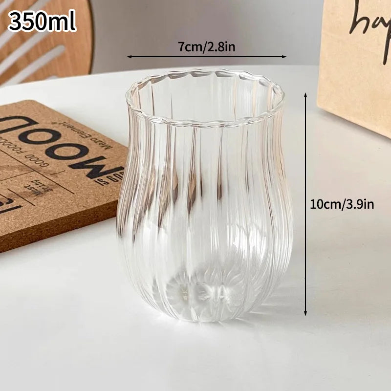 A clear glass tumbler with vertical ribbed texture is shown next to a measurement scale.