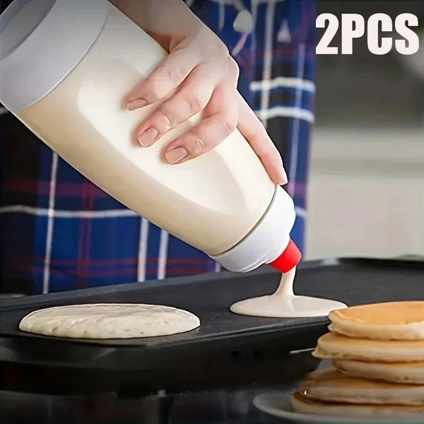 Eine Hand gießt weißes Teig in Pfannkuchen auf eine schwarze Griddle.