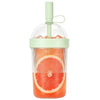 A clear reusable tumbler coffee cup filled with sliced grapefruit and topped with a light green straw lid.
