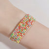 A stack of multi-colored acrylic elastic bracelets worn on a person's wrist.