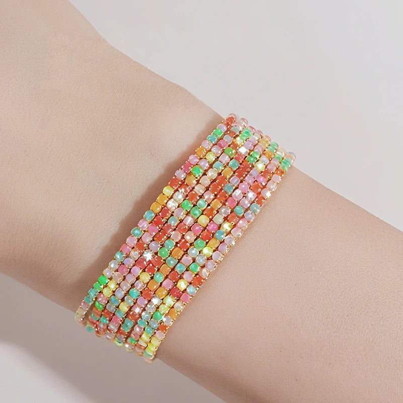 A stack of multi-colored acrylic elastic bracelets worn on a person's wrist.