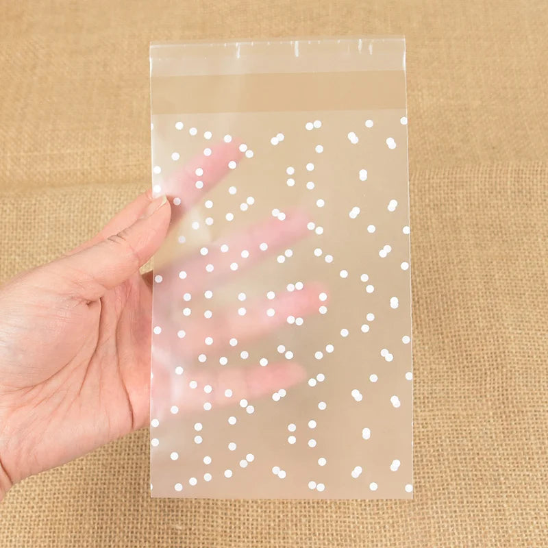 A hand holds a clear plastic bag filled with white dots, used for DIY storage of candy cookies.