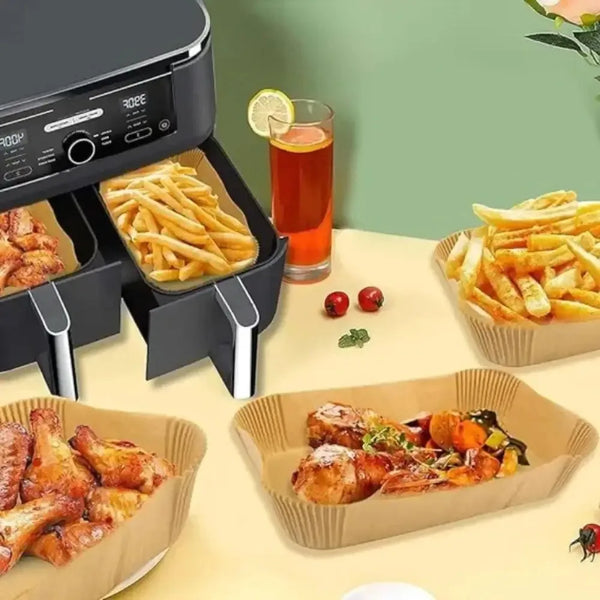 Wiederverwendbare Airfryer mit Speisen wie Pommes und Hähnchenstücken in Papierformen.
